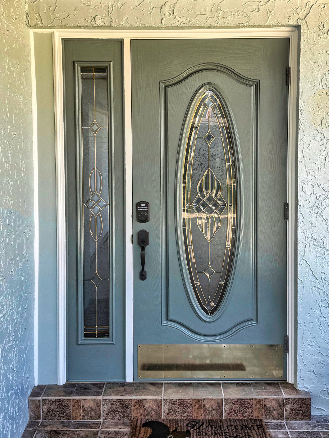 Freshly repainted sage green front entry door with crisp white trim on a Melbourne, FL home after exterior door painting by Launch Painting Co.