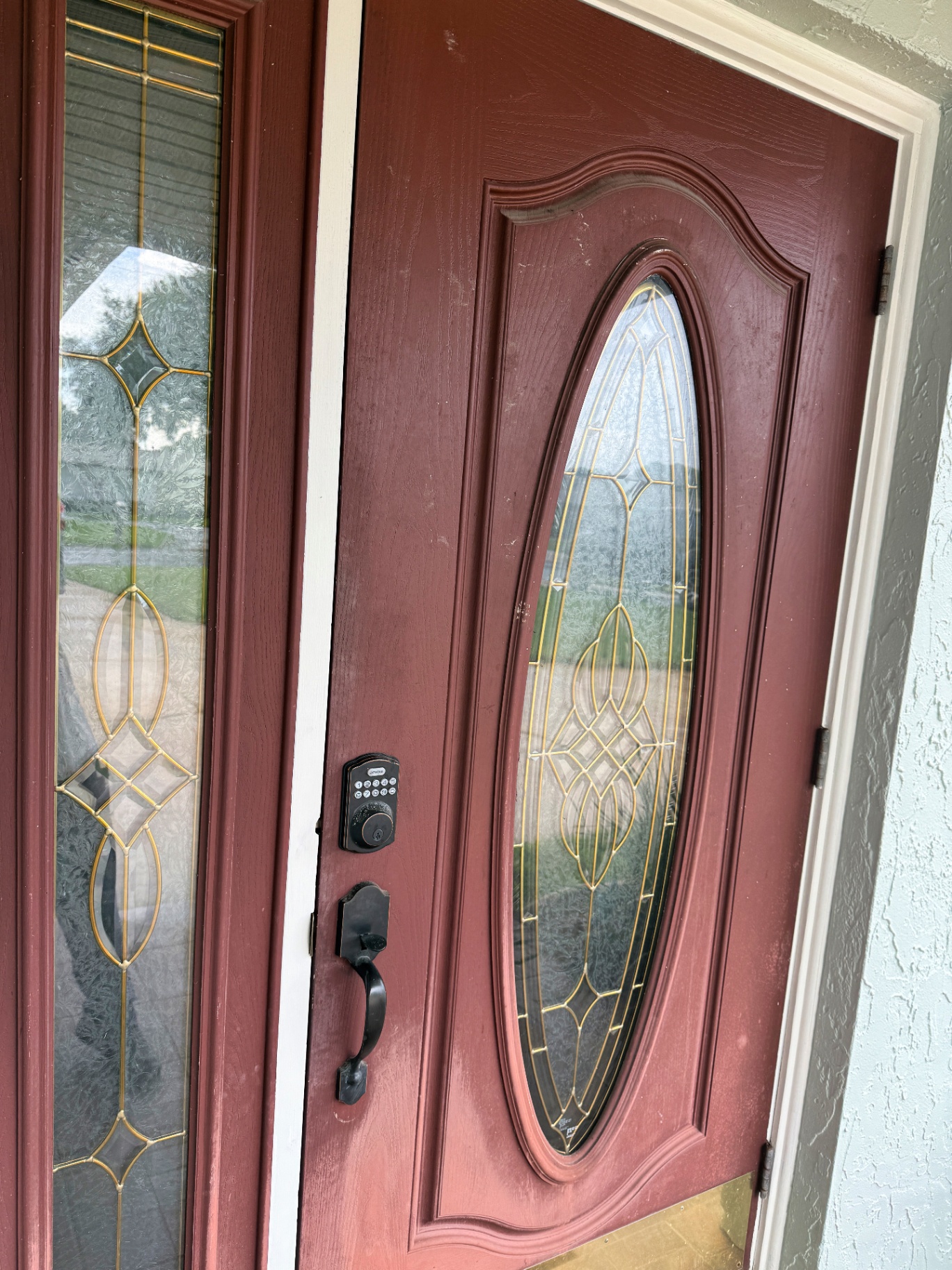 Worn burgundy front entry door with faded finish on a Melbourne, FL home before repainting by Launch Painting Co.